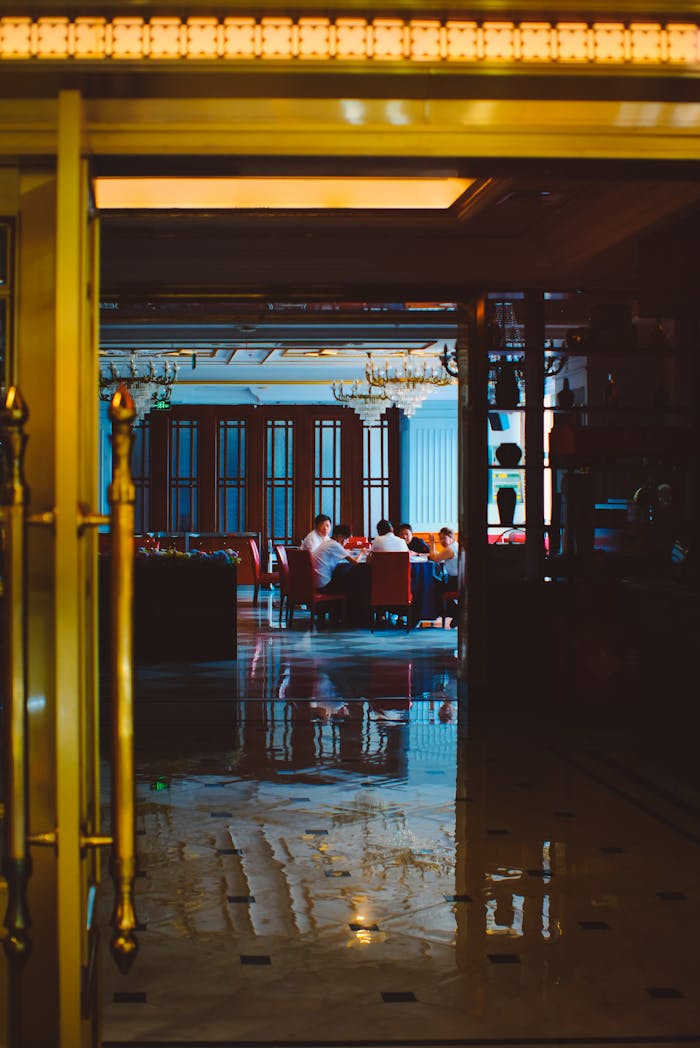 View of an elegant restaurant through golden doors, showcasing intimate dining with a warm ambiance.