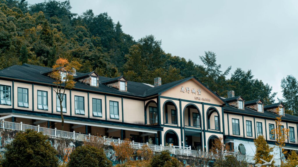 Charming mansion facade surrounded by lush forest, featuring classic architecture and peaceful ambiance.