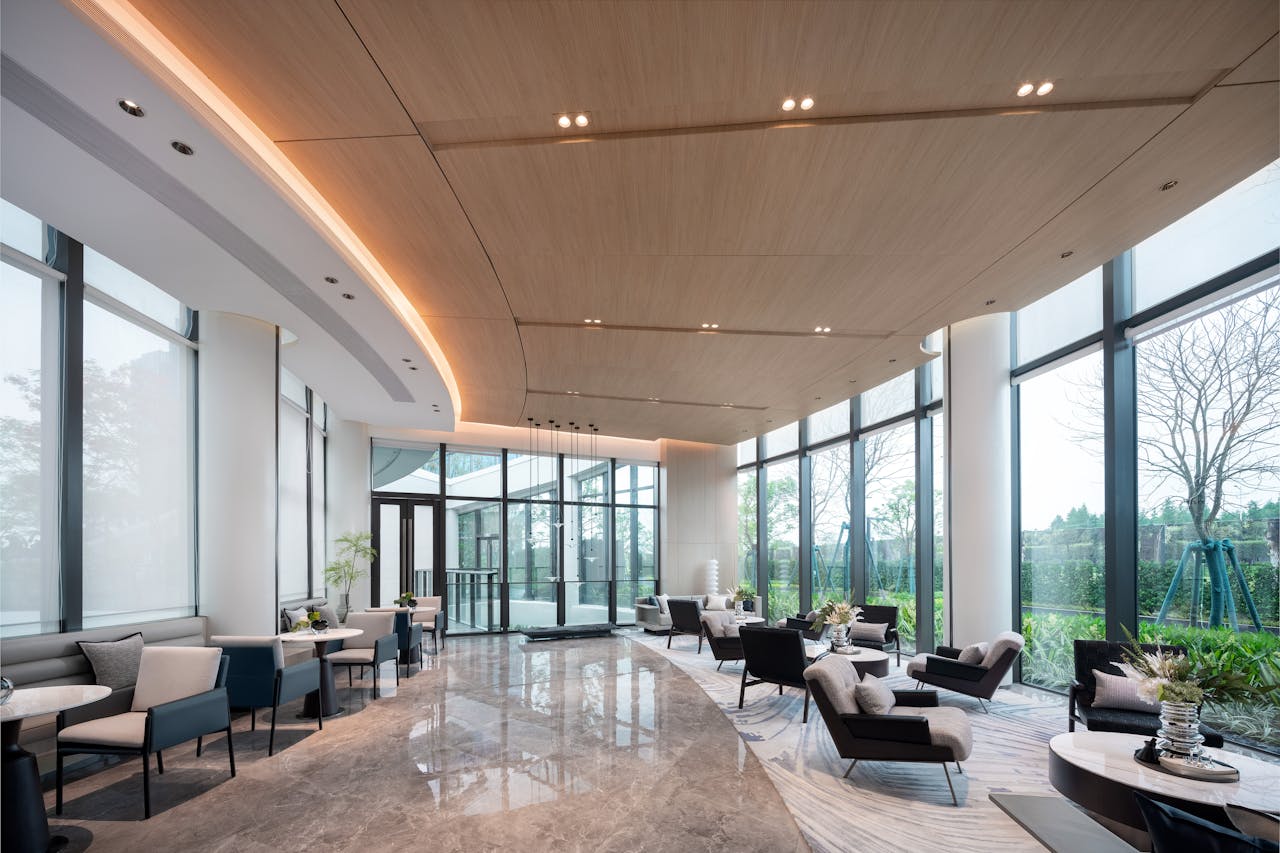 Elegant lounge with seating, plants, and large windows offering greenery views.